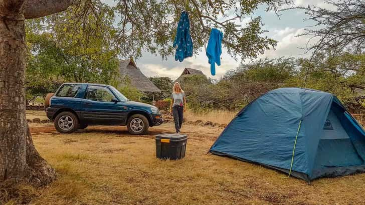 Lotte bij de auto en tent op haar roadtrip door Tanzania