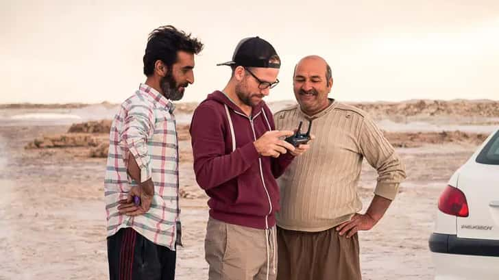 Twee mannen kijken toe hoe Erick de drone bestuurt.